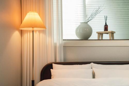 a bedroom with a bed with a lamp and a window at Dal Stay in Seoul