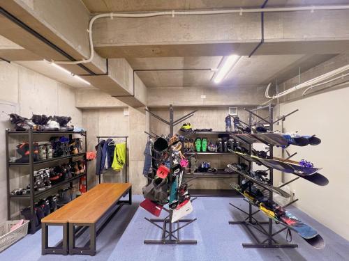 a room with a table and a bunch of ski equipment at 雪玉Snowball Hostel in Furano