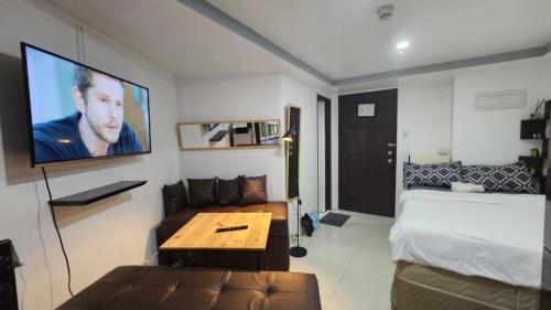 バギオにあるBaguio Bliss by Burnham Hill Condominiumのベッドとソファとテレビのある部屋