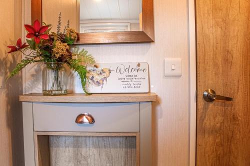 a vase of flowers on a table next to a door at Bumble Lodge New Forest in Landford
