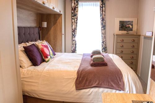 a bedroom with a bed with two towels on it at Bumble Lodge New Forest in Landford