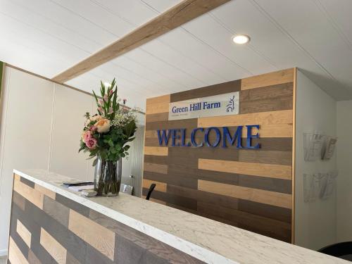 a vase of flowers on a counter with a welcome sign at Bumble Lodge New Forest in Landford