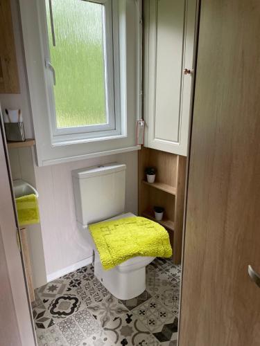 a small bathroom with a toilet with a yellow seat at Bumble Lodge New Forest in Landford