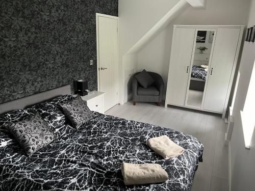 a bedroom with a black and white bed and a chair at Plough Cottage in Bradfield