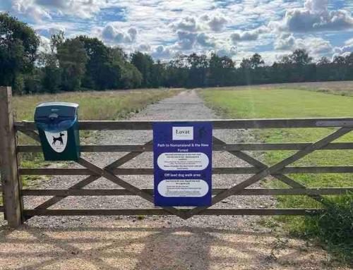 a sign on a fence with a trash can at Bumble Lodge New Forest in Landford