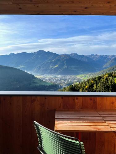 a wooden balcony with a table and chairs and mountains at Schallerhof Sterzing - Deine Auszeit mit Ausblick in unseren Ferienwohnungen auf dem Bergbauernhof in Südtirol in Vipiteno
