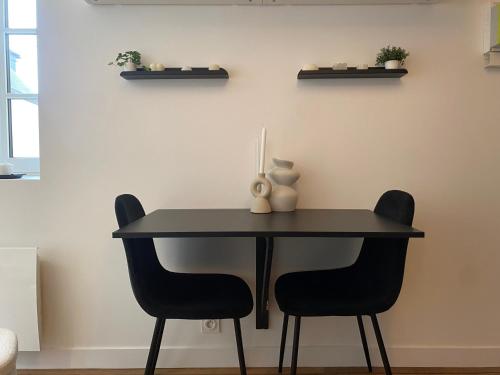 une table noire avec deux chaises et un vase sur elle dans l'établissement Cocon cosy hyper centre, à Saint-Malo