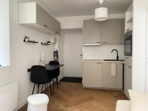 une cuisine avec des armoires blanches et une table et des chaises dans l'établissement Cocon cosy hyper centre, à Saint-Malo