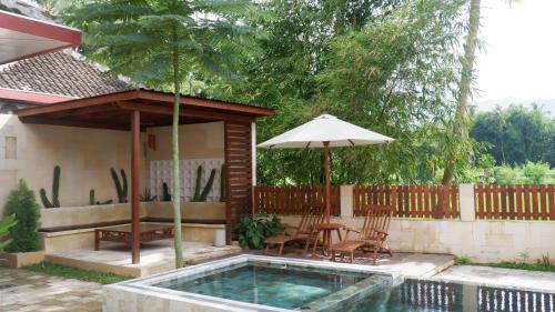 a pool with a table and chairs and an umbrella at Nalendro Villa Borobudur in Borobudur
