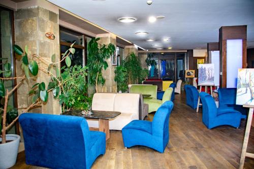 a waiting room with blue chairs and plants at Gardenia Park Hotel in Bansko