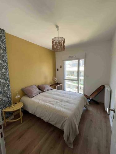 une chambre avec un grand lit et une fenêtre dans l'établissement Appartement spacieux et lumineux St Malo Paramé, à Saint-Malo