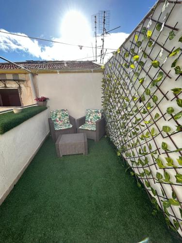 a patio with two chairs and a wall with plants at Palermo Centro Affittacamere Spina in Palermo