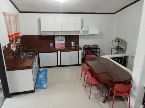a kitchen with a wooden table and red chairs at Balay de Sorsogon in San Lorenzo