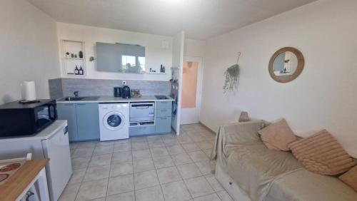 un salon avec un canapé et une cuisine dans l'établissement Studio paisible belle vue et proche de la mer, à Cavalaire-sur-Mer