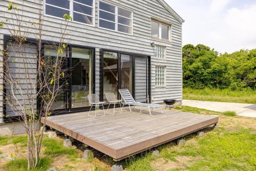 two chairs on a wooden deck in front of a house at Sea and Gallery house館山 in Tateyama