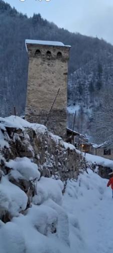 a stone tower on top of a snow covered hill at Lela Guest House in Mestia