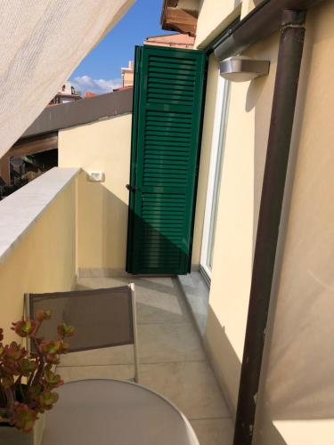 a green door on a balcony with a chair at B&B Borgo Marina in Bordighera