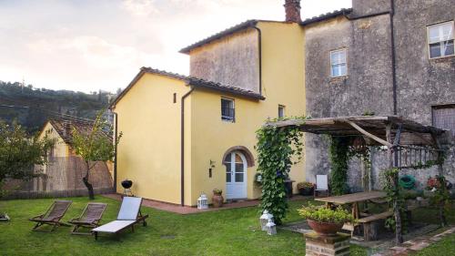 a yellow house with a table and chairs in the yard at Rustico Dora in Camaiore