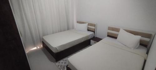 a small room with two beds with white pillows at Sea View Ras El Hekma Rental Chalet in Jalāl