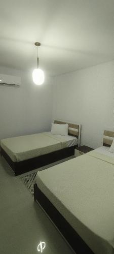 a room with two beds and a light at Sea View Ras El Hekma Rental Chalet in Jalāl