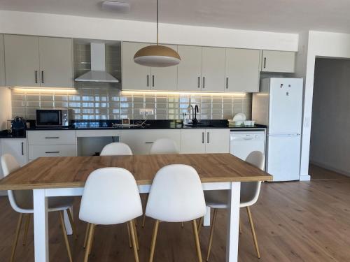 Una cocina con una mesa de madera y sillas blancas. en Excelentes Vistas ante el Mar, en Sant Carles de la Ràpita