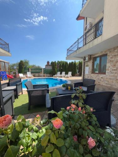 a patio with chairs and flowers and a swimming pool at Апартхотел Созополски перли in Sozopol