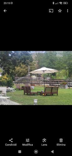 two benches and an umbrella in a park at Il Rio Grande in Beverino