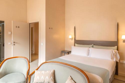 a bedroom with a large white bed and chairs at SólleRooms in Sóller