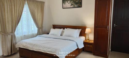 a bedroom with a bed with white sheets and a window at Anaara Escapes in Turavūr