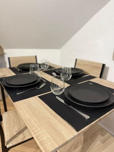 - une table avec des assiettes noires et des verres à vin dans l'établissement Les Combles de Colbert- hyper center, à Troyes