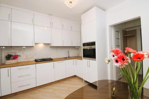 a kitchen with white cabinets and a vase of flowers at Apartament Słowackiego in Oświęcim