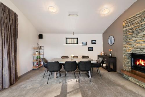 a dining room with a table and chairs and a fireplace at Closeburn LakeView House in Queenstown