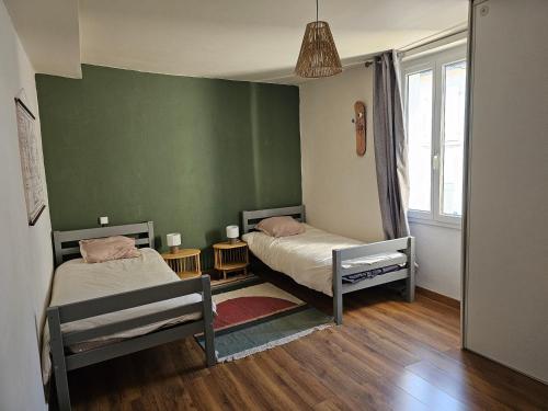 two beds in a room with green walls and wooden floors at La charmante in Puyoô