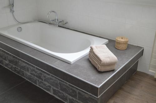 y baño con bañera, toalla y taburete. en Villa Josiane, en Oostduinkerke