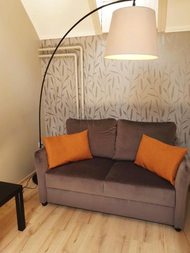 a couch with two orange pillows in a living room at Indium City Panzió in Eger