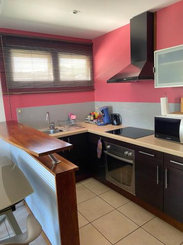 a kitchen with red walls and a counter top at Coquet F2 Quiet & Secure Vallée des Colons À in Noumea
