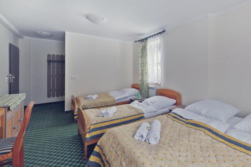 a hotel room with three beds with towels on them at Pensjonat Limba in Duszniki Zdrój