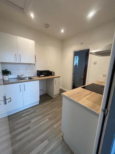 a kitchen with white cabinets and a wooden floor at Spacious Apartment near train station with a parking space in Birmingham