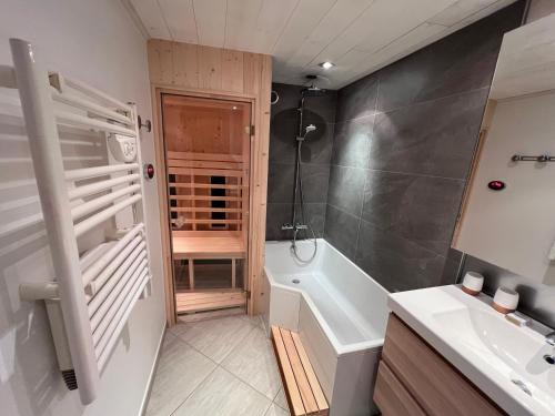 łazienka z prysznicem, wanną i umywalką w obiekcie Chalet des Grangettes avec jardin, sauna et Appli Roadbook - Huez w mieście LʼHuez