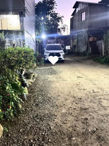 a white car parked next to a building with a heart on it at Pio Transient House in Tanay