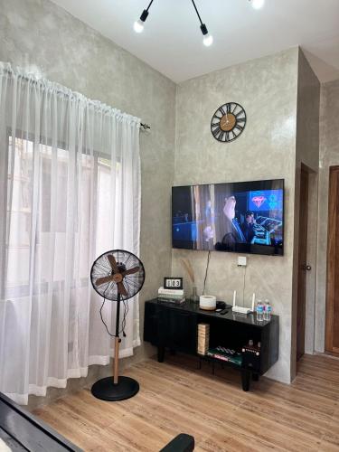 a living room with a flat screen tv and a fan at Pio Transient House in Tanay