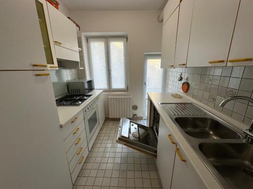eine Küche mit weißen Schränken und einer Spüle in der Unterkunft Appartamento 3 camere con vista mare - Agenzia Cocal in Caorle