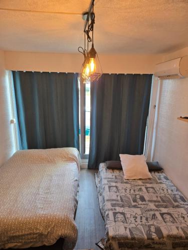 une chambre avec deux lits et un lustre dans l'établissement Studio cabine, au Grau-du-Roi