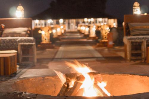 a fire burns in a fire pit at night at Paradise Luxury Camp in Merzouga