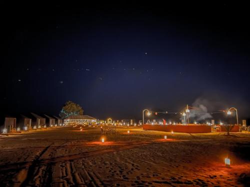 a beach at night with lights in the sand at Paradise Luxury Camp in Merzouga