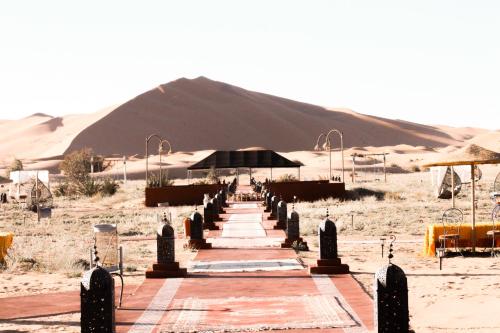 a pathway in the desert with a mountain in the background at Paradise Luxury Camp in Merzouga