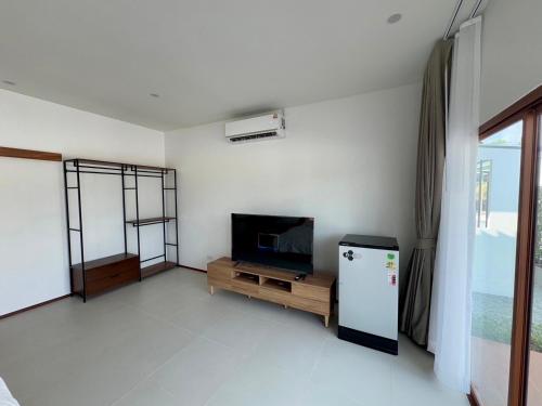 a living room with a refrigerator and a tv at Maikhao Beach Guest House in Mai Khao Beach