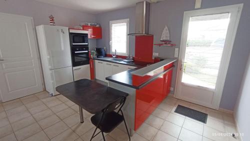 une cuisine avec des appareils rouges et blancs et une table dans l'établissement Grande maison 100m2 7 personnes 3 chambres, à Bretignolles-sur-Mer