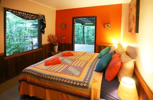 a bedroom with orange walls and a bed with pillows at Tropical Bliss bed and breakfast in Mena Creek