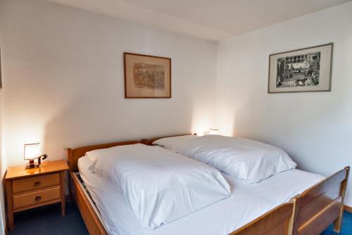 a bedroom with a bed with white sheets and a nightstand at Chesa Allegria - Sils Maria in Sils Maria